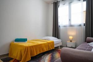 a bedroom with a bed with a yellow blanket on it at Ecumes Sauvages - DODOTERLA in Manapany-les Bains