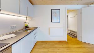 a kitchen with white cabinets and a wooden floor at HEIMATEL - Ferienhaus Prinz-Lui in Scheidegg +28 photos