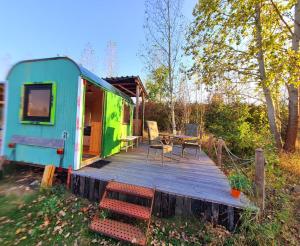 a blue and green house with a wooden deck at Bauwagen, Tiny House in Warnitz am Oberuckersee in Melzow