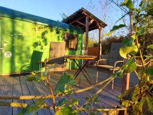 a green trailer with two chairs and a table on a deck at Bauwagen, Tiny House in Warnitz am Oberuckersee in Melzow