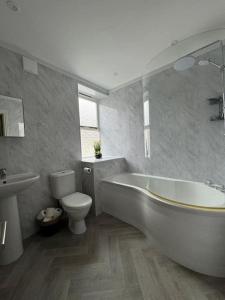 a bathroom with a white tub and a toilet at Townhouse in Weymouth, Dorset in Melcombe Regis