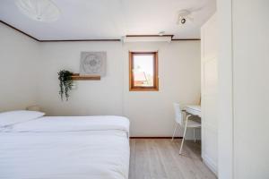 a bedroom with two beds and a table and a window at Chalet omringd door groen op de Veluwe in Putten