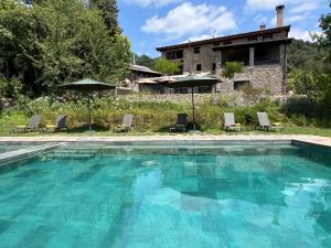 a swimming pool in front of a house at MAS CAMPASSOL in Sant Felíu de Pallarols