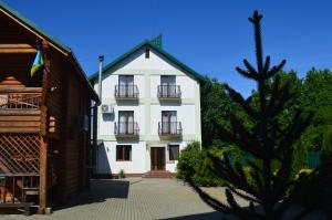 a white building with two balconies and a tree at Садиба "Мапа" in Berehove