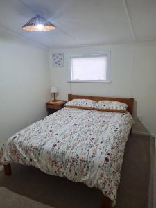 a bedroom with a bed with a comforter and a window at Coastal Comfort on Cook Drive in Whitianga +6 photos