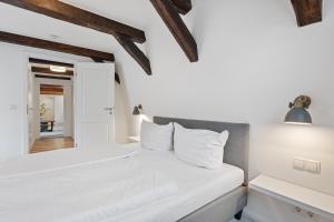 a bedroom with white walls and a bed with white pillows at PEMATRA Haus Waterkant - FeWo Piratennest in Travemünde