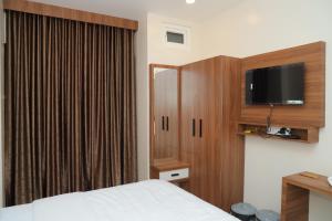 a bedroom with a bed and a cabinet with a tv at Hotel BR Grand in Coimbatore