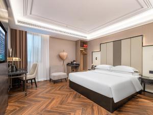 sypialnia z dużym białym łóżkiem i biurkiem w obiekcie 锦江都城 新沂行政中心北京路店 w mieście Xinyi