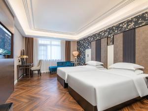 pokój hotelowy z dwoma łóżkami i biurkiem w obiekcie 锦江都城 新沂行政中心北京路店 w mieście Xinyi