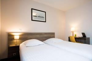 Un dormitorio con dos camas blancas y un cuadro en la pared. en Comfort Aparthotel Saint-Nazaire Les Portes de l Ocean, en Saint-Nazaire
