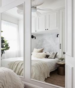 a mirror in a white bedroom with a bed at Exclusive Darling Apt Harbour View Balcony in Sydney