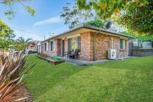 a brick house with a lawn in front of it at Family Coastal Escape Narrawallee NSW in Narrawallee