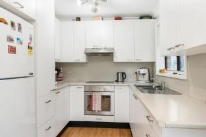 a white kitchen with white cabinets and a sink at Family Coastal Escape Narrawallee NSW in Narrawallee +10 photos