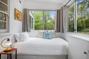 Una habitación blanca con una cama y una ventana. en Deodar Cottage Amid Century Old Trees, en Wentworth Falls