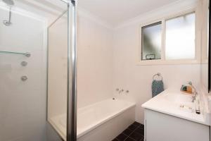 a white bathroom with a shower and a sink at Azure Sands Ocean Views in Batehaven in Batehaven +38 photos