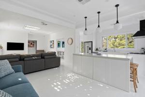 a white living room with a couch and a kitchen at Hillside Hamptons Indoor Fire and Fire Pit in Terrigal