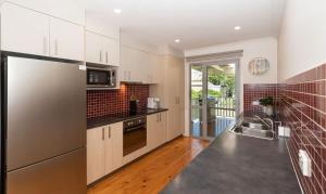 a kitchen with white cabinets and a stainless steel refrigerator at Azure Sands Ocean Views in Batehaven in Batehaven