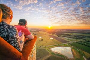 two people sitting on the edge of a tower looking at the sunset at Blue Wren Cottage on Edith - A Fireside Retreat in Wine Country in Cessnock
