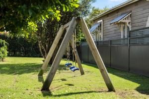 a wooden swing set in the yard of a house at Blue Wren Cottage on Edith - A Fireside Retreat in Wine Country in Cessnock