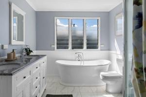 a bathroom with a tub and a sink and a toilet at Blue Wren Cottage on Edith - A Fireside Retreat in Wine Country in Cessnock