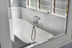 a bath tub in a bathroom with a mirror at Blue Wren Cottage on Edith - A Fireside Retreat in Wine Country in Cessnock