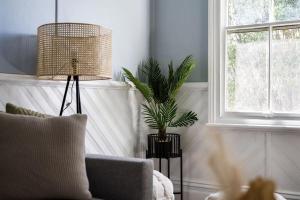 a living room with a couch and a potted plant at Blue Wren Cottage on Edith - A Fireside Retreat in Wine Country in Cessnock