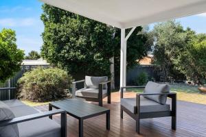 a patio with chairs and a table on a deck at Blue Wren Cottage on Edith - A Fireside Retreat in Wine Country in Cessnock