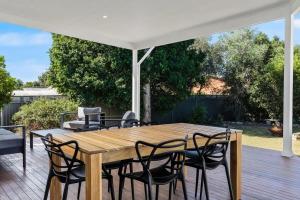 a wooden table and chairs on a patio at Blue Wren Cottage on Edith - A Fireside Retreat in Wine Country in Cessnock