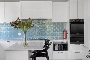 a white kitchen with a vase of flowers on a table at Blue Wren Cottage on Edith - A Fireside Retreat in Wine Country in Cessnock