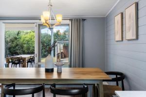 a dining room with a wooden table and black chairs at Blue Wren Cottage on Edith - A Fireside Retreat in Wine Country in Cessnock