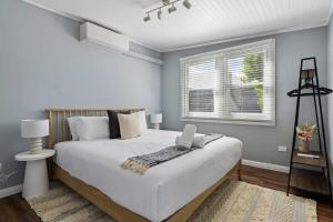 a bedroom with a large white bed and a window at Blue Wren Cottage on Edith - A Fireside Retreat in Wine Country in Cessnock