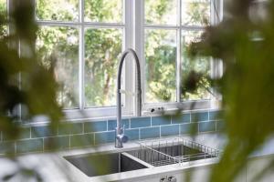 a sink in a kitchen with three windows at Blue Wren Cottage on Edith - A Fireside Retreat in Wine Country in Cessnock