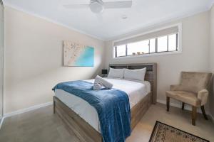 a bedroom with a bed and a chair and a window at Oak Retreat Bliss by the Beach in Warriewood