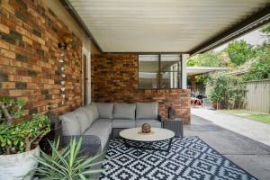 a patio with a couch and a table at Oak Retreat Bliss by the Beach in Warriewood