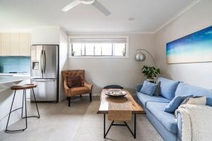 a living room with a blue couch and a kitchen at Oak Retreat Bliss by the Beach in Warriewood