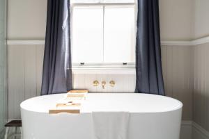 eine weiße Badewanne im Bad mit Fenster in der Unterkunft Luxury Heritage Home 10min Walk to Scenic World in Katoomba + 44 Fotos