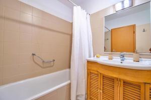 a bathroom with a sink and a tub and a mirror at Estúdio Costinha - Madeira in Garajau