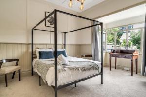 ein Schlafzimmer mit einem schwarzen Himmelbett und einem Schreibtisch in der Unterkunft Luxury Heritage Home 10min Walk to Scenic World in Katoomba