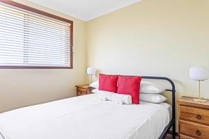 a bedroom with a bed with red and white pillows at Coastal Delight In Shellcove in Dunmore