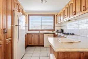 a kitchen with wooden cabinets and a white refrigerator at Coastal Delight In Shellcove in Dunmore