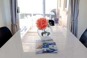 a vase with a flower on a table with a magazine at Coastal Delight In Shellcove in Dunmore