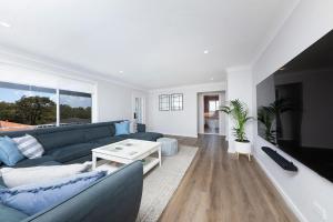 a living room with a blue couch and a table at Four Palms Forster Luxe Spacious Pet Friendly in Forster