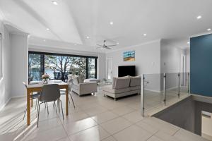 a dining room and living room with a table and chairs at Waterfront Treetops Getaway in Wangi Wangi