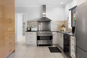 a kitchen with a stove and a refrigerator at Waterfront Treetops Getaway in Wangi Wangi +22 photos
