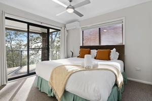 a bedroom with a large bed and large windows at Waterfront Treetops Getaway in Wangi Wangi