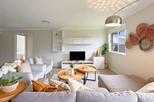 a living room with couches and a tv at Vineyard Oasis Heart of the Hunter in Cessnock