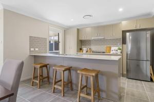 a kitchen with a stainless steel refrigerator and stools at Vineyard Oasis Heart of the Hunter in Cessnock