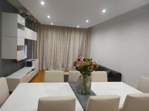a dining room with white tables and chairs and a vase of flowers at ADALBERTO NASCIMENTO LUXURY APARTA-HOSTEL At COLINAS DO CRUZEIRO in Odivelas