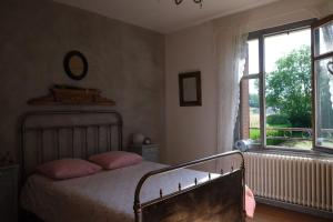 a bedroom with a bed with pink pillows and a window at L’hors-du temps in Le Tartre