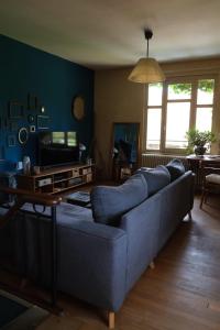 a living room with a blue couch and a television at L’hors-du temps in Le Tartre